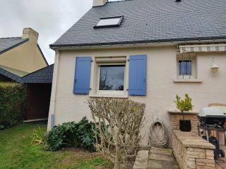 6746d82b9fc1d Une maison avec des volets bleus et un toit en ardoise, entourée d'un jardin bien entretenu avec un barbecue et des plantes