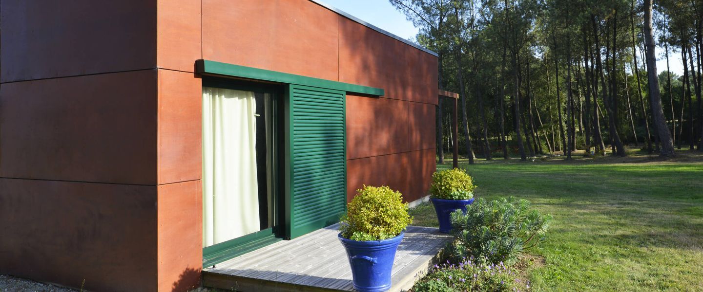 Volets coulissants verts à lamelles fixes sur terrasse de maison moderne