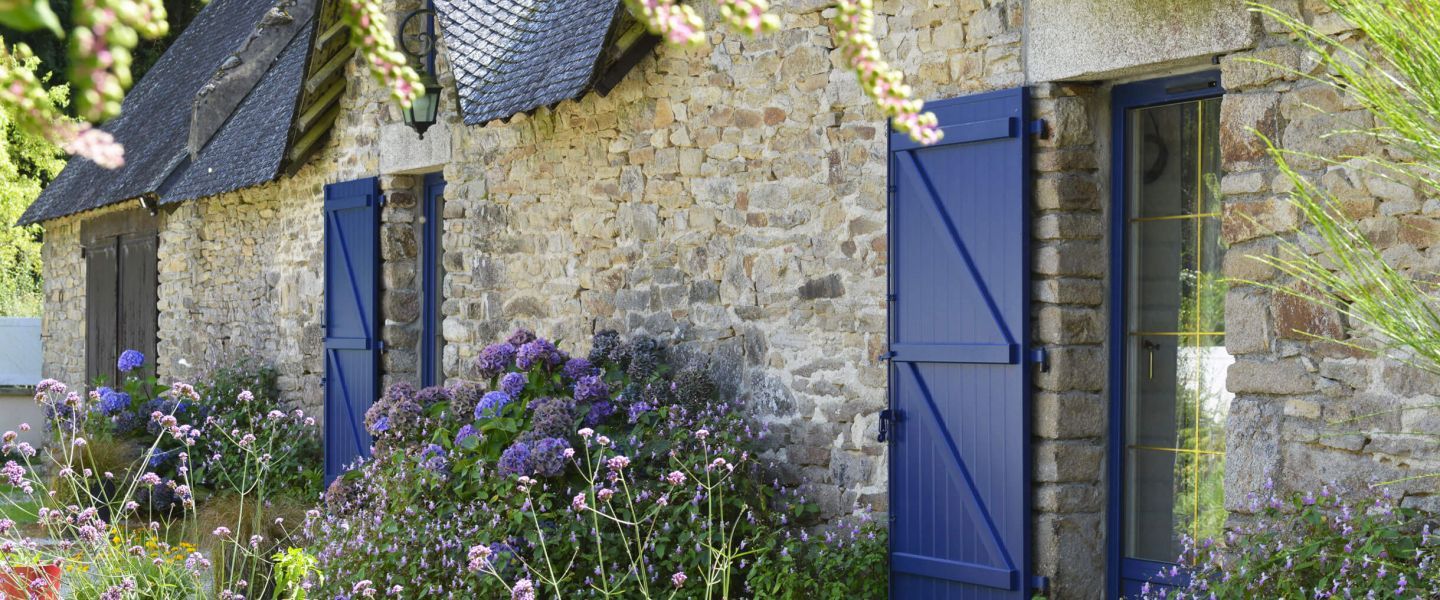 volets-battants-atout-banniere.jpg Volets battants bleu sur facade en pierre et fleurie