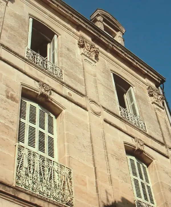 Volet lamelle fixe blanc facade en pierre batiment ancien en ville