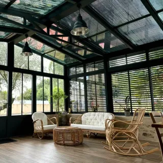 choisir_le_verandier_by_TRYBA.webp Une véranda lumineuse et moderne avec des meubles en rotin confortables, offrant une vue sur le jardin extérieur.