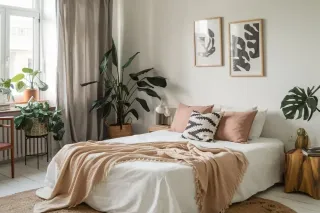 coffres_de_volets_roulants.webp Une chambre lumineuse et harmonieuse avec un lit accueillant, entouré de plantes vertes et décoré de coussins et plaids dans des
