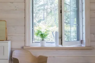 eliminer_poussiere_ventilation.webp Une fenêtre ouverte laisse entrer la lumière naturelle dans une pièce en bois clair, avec une plante en pot sur le rebord.
