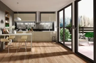 erreur_ventilation.webp Cuisine moderne avec îlot central, parquet en bois clair et grandes baies vitrées donnant sur un jardin.