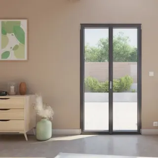 fenetre_aluminium_couleur.webp Une élégante porte-fenêtre noire s'ouvrant sur une terrasse, encadrée par un intérieur moderne et minimaliste avec une touche de