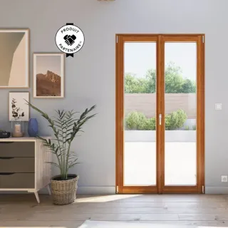 fenetre_bois_couleur.webp Une porte-fenêtre en bois donne sur une terrasse ensoleillée, entourée de verdure, avec une plante d'intérieur et des photos enc
