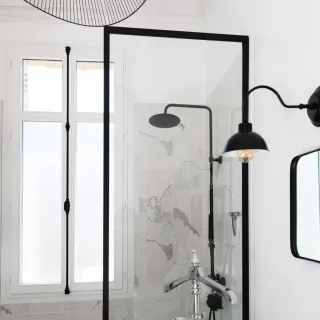 fenetre_vitrage_ornementaux.webp Salle de bain élégante avec douche à l'italienne, paroi vitrée et éléments noirs modernes.