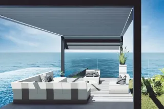 fonctionnement_pergola.webp Terrasse moderne avec salon extérieur surplombant l'océan avec vue panoramique.