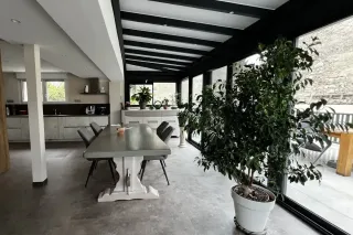 innovation_esthetique_veranda.webp Salle à manger lumineuse et moderne, agrémentée de grandes baies vitrées et de plantes vertes.