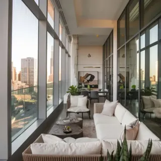 Isolation_phonique_fenetre_balcon.webp Une élégante terrasse moderne avec un canapé confortable et une vue panoramique sur les gratte-ciel de la ville.