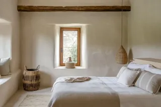 pont_thermique_chambre_fenetre.webp Chambre lumineuse et minimaliste avec des accents naturels, incluant un lit confortable, des murs blancs, et un éclairage suspendu en os