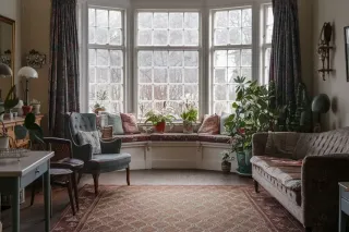 pont_thermique_salon_fenetre.webp Un salon lumineux et chaleureux, décoré avec des fauteuils confortables, des coussins colorés, et des plantes, offrant une ambiance accueillante