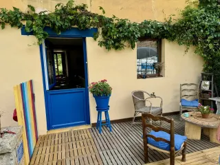 portes-tryba-pvc-bleu.webp Une terrasse chaleureuse avec des chaises en bois et en osier, un mur recouvert de lierre, et une porte bleue écl