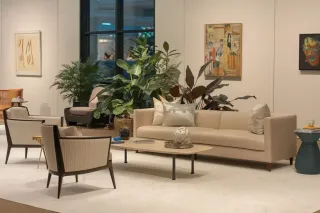 prix_double_vitrage.webp Un salon moderne et élégant avec des meubles aux tons neutres, des plantes vertes luxuriantes et des œuvres d'art accrochées aux murs.