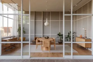 triple_vitrage_confort.webp Un intérieur moderne avec une salle à manger minimaliste comprenant une table en bois, des chaises assorties et des plantes décoratives, visible à travers