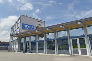 TRYBA_SUISSE_prsentation_socit.webp Le bâtiment moderne de Tryba, fabricant de fenêtres et portes, est doté d'une façade vitrée et d'un large panneau bleu sous un ciel part