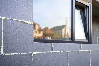 visuel_bloc_2.webp Construction de mur avec isolation en mousse expansive autour d'une fenêtre.